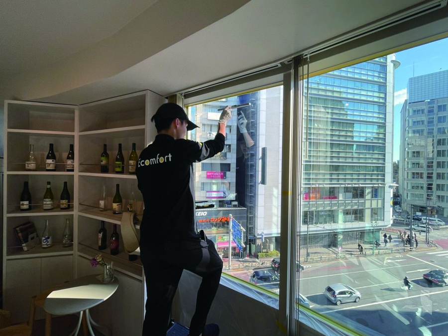 窓ガラスにEGLASSを施工するスタッフ